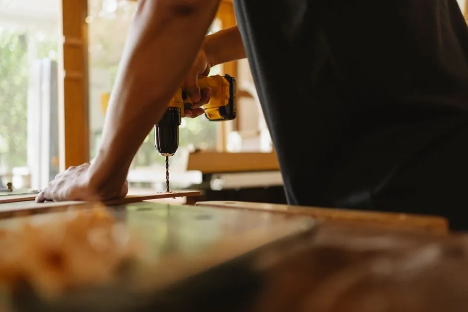 Benjamin Fouché, artisan multiservices, perçant une planche dans un atelier lumineux